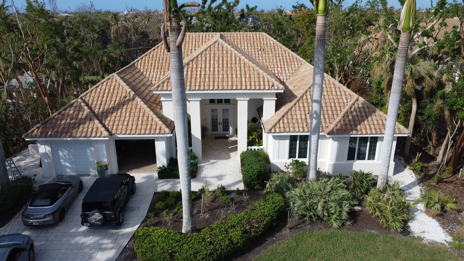 Southwest Florida home with a new flat tile roof, columns and palms at the entry